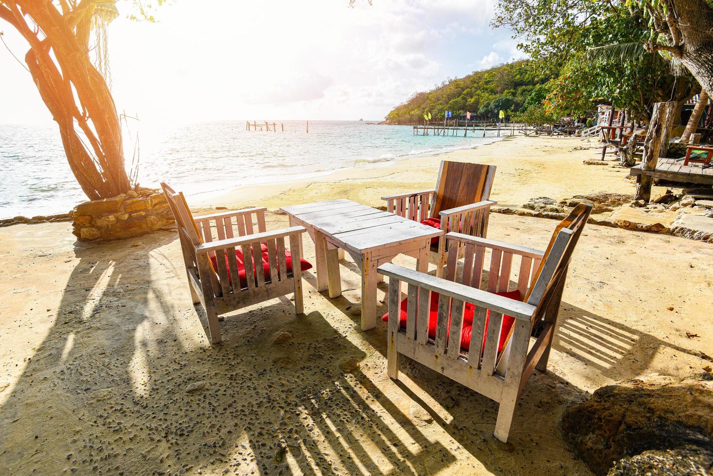 mesa de madeira posta na praia vista das ondas do mar e paisagem costeira - paisagem marítima com mesa e cadeira ilha tropical com fundo de céu azul oceano no resort tailândia férias de verão na praia foto