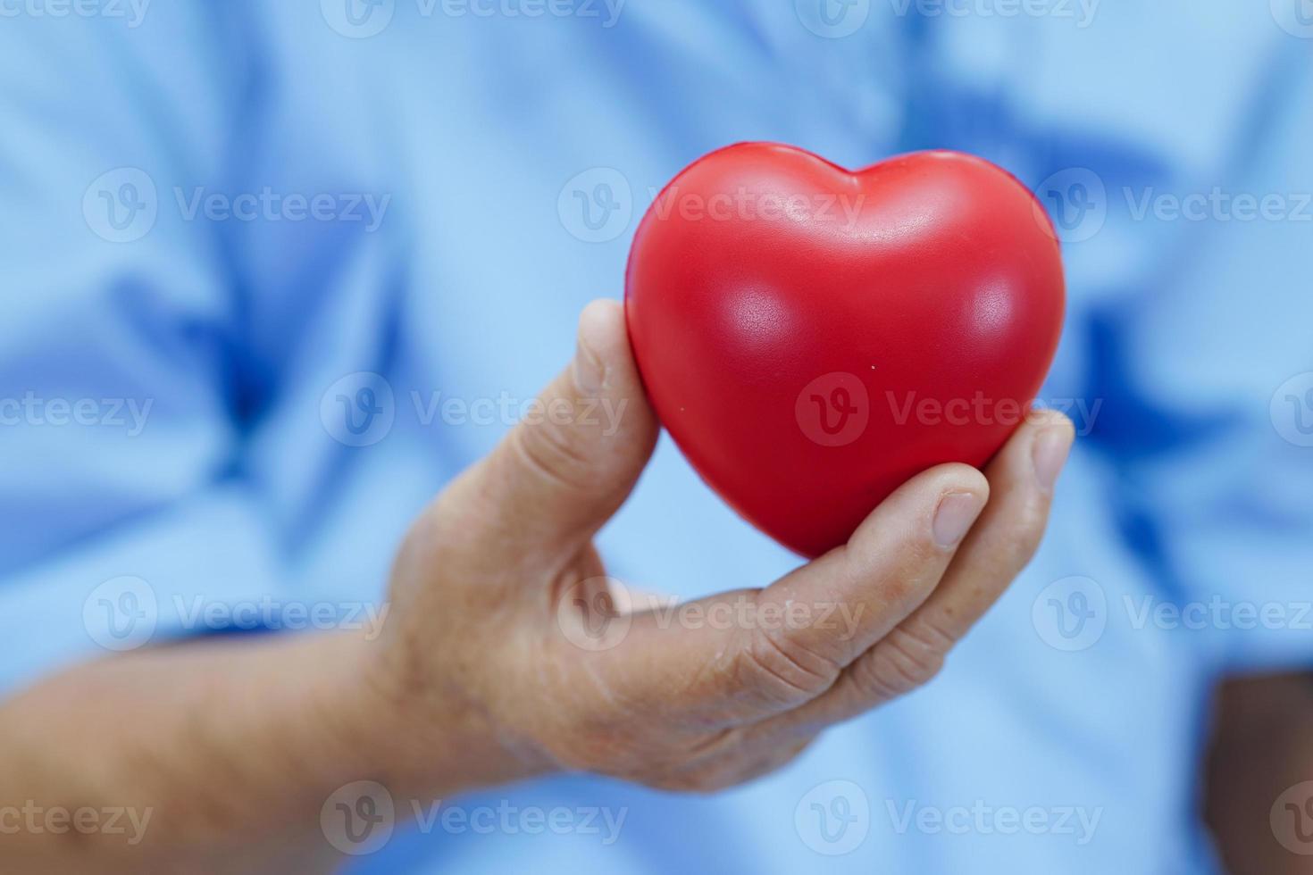 paciente asiática idosa idosa segurando coração vermelho no hospital. foto