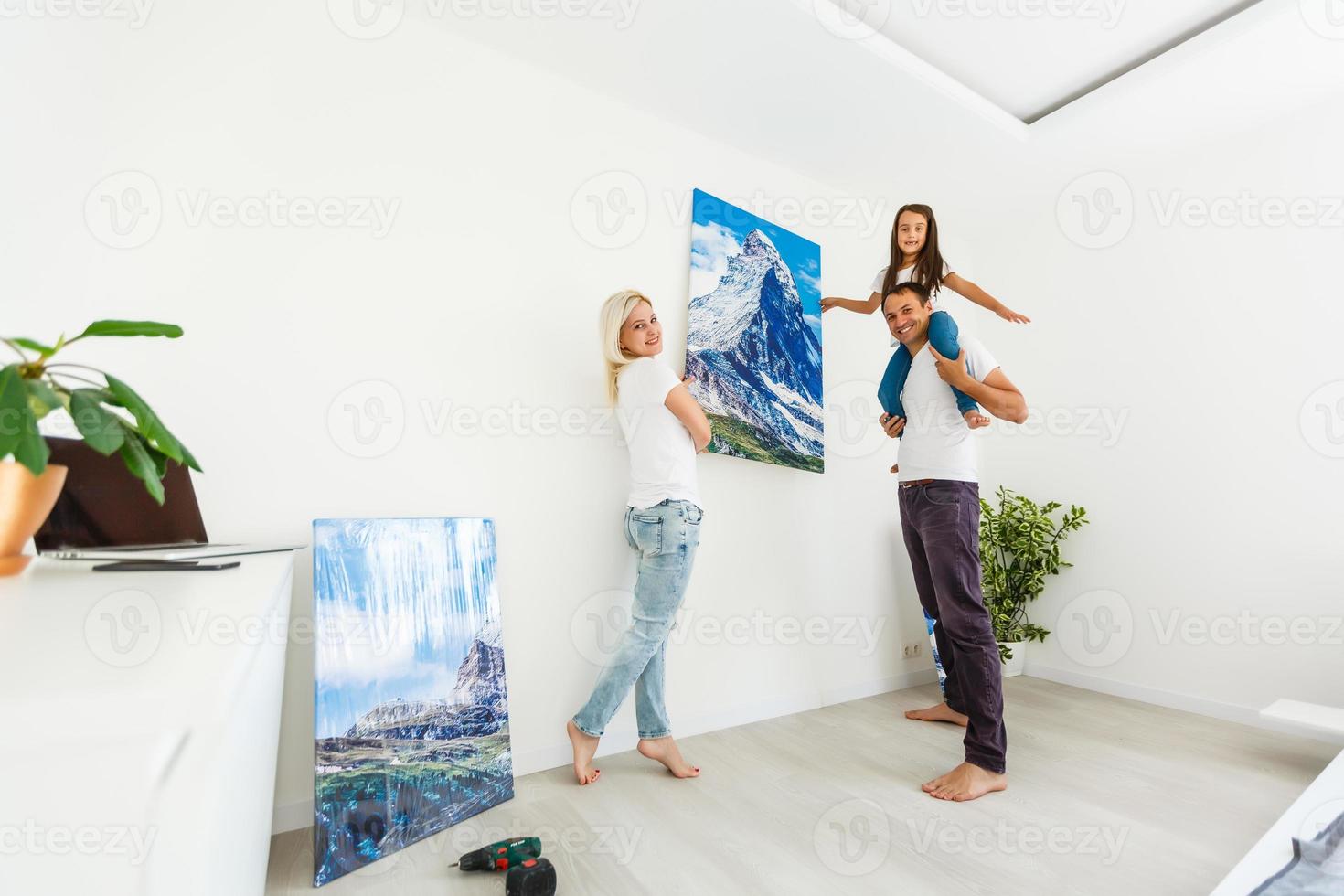 família pendura uma grande tela de fotos em casa