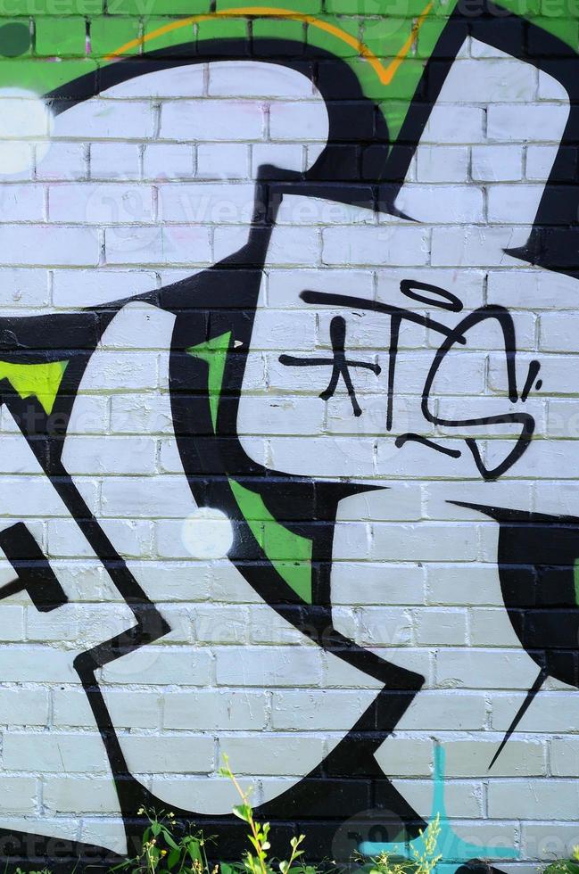 fragmento de desenhos de grafite. a parede antiga decorada com manchas de tinta no estilo da cultura da arte de rua. textura de fundo colorido em tons de verde foto