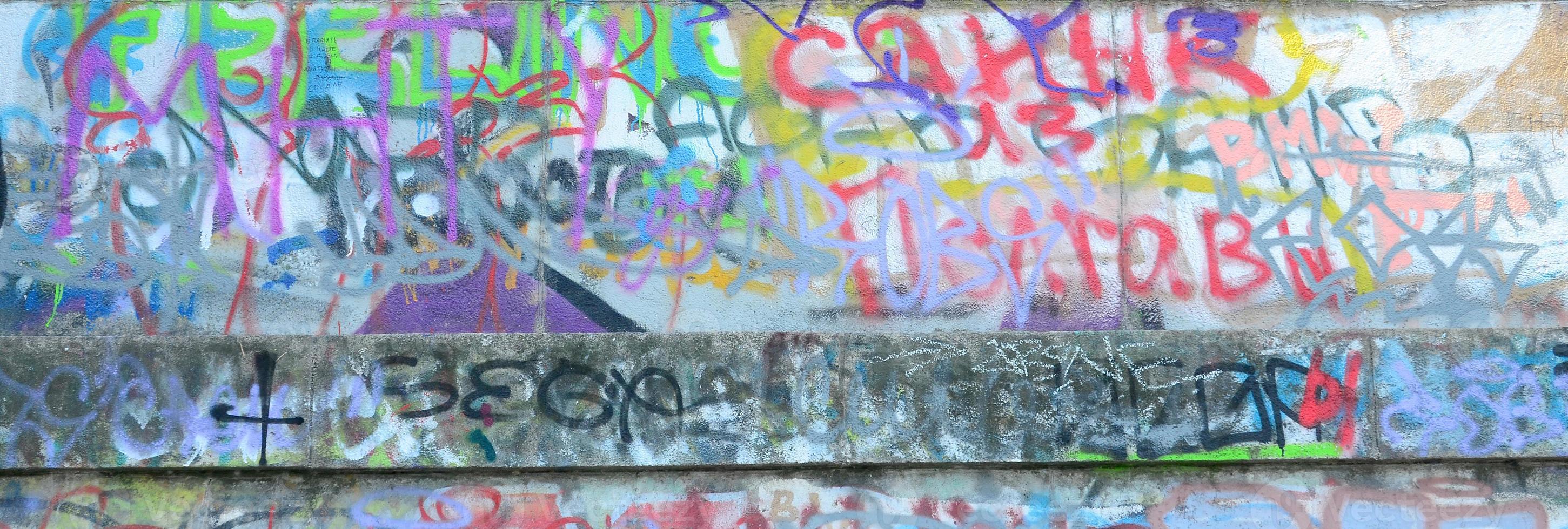 fragmento de tags de graffiti. a velha parede está estragada com manchas de tinta no estilo da cultura da arte de rua foto