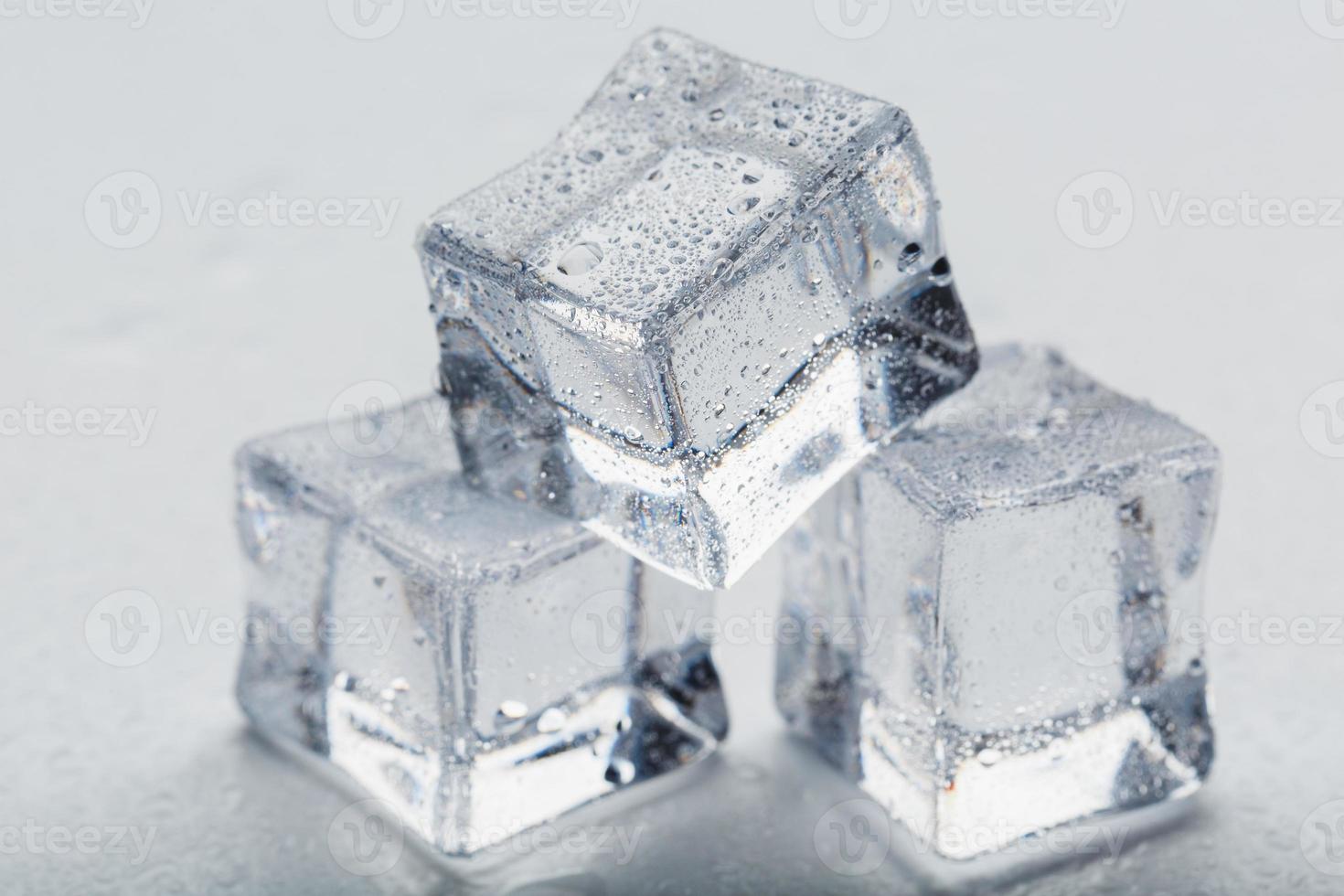 cubos de gelo na forma de uma pirâmide com água cai de perto - em macro sobre um fundo branco. foto