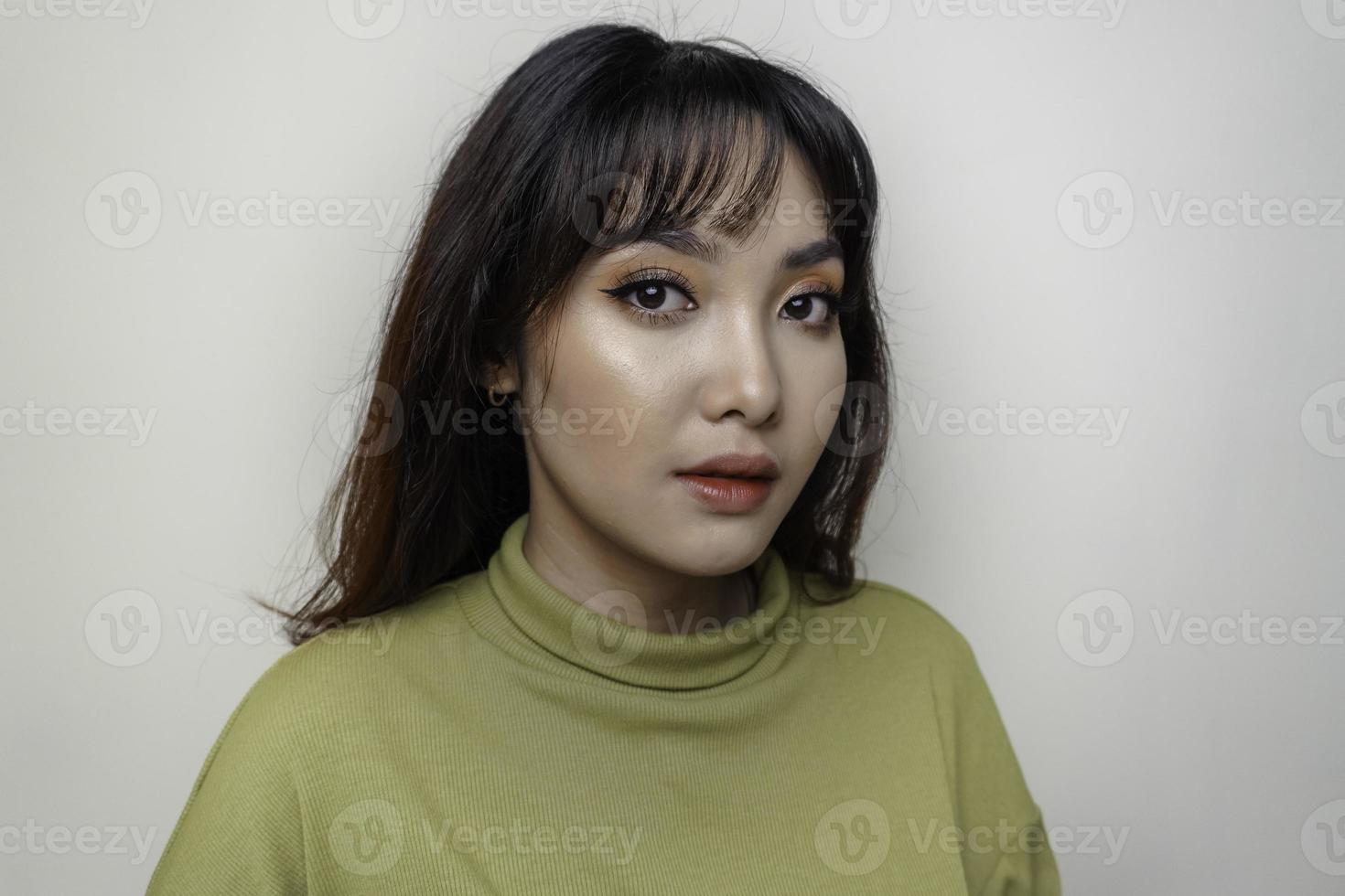 um rosto alegre de beleza da jovem modelo asiática vestindo top verde. tratamento facial de beleza para a pele, spa, conceito de saúde feminina. foto