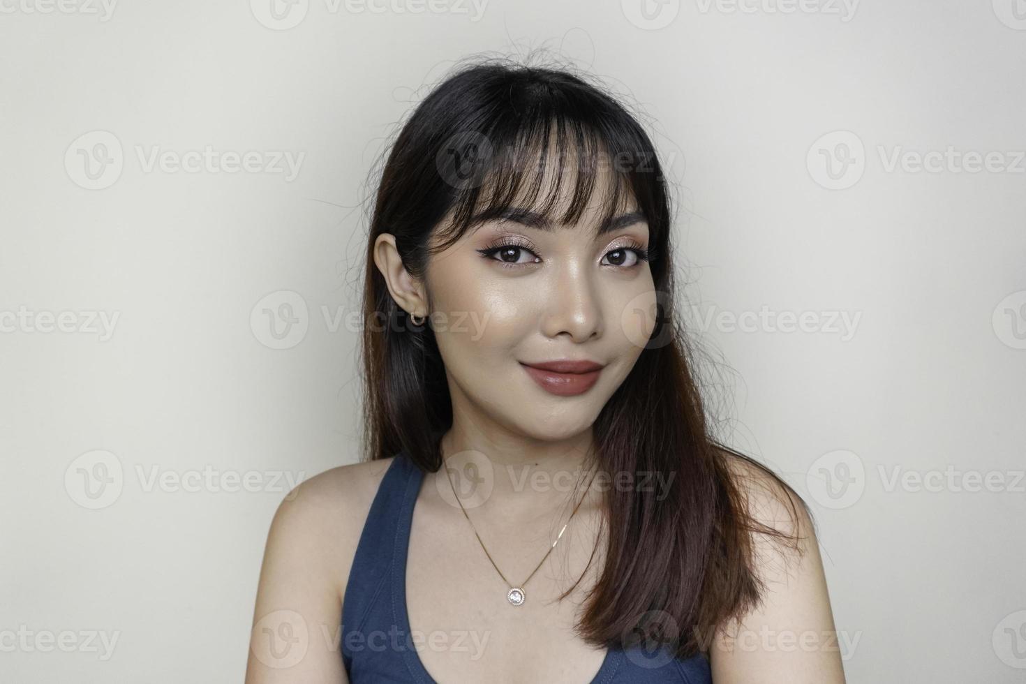 um rosto alegre de beleza da jovem modelo asiática vestindo top verde-azulado. maquiagem skincare beleza tratamento facial, spa, conceito de saúde feminina. foto