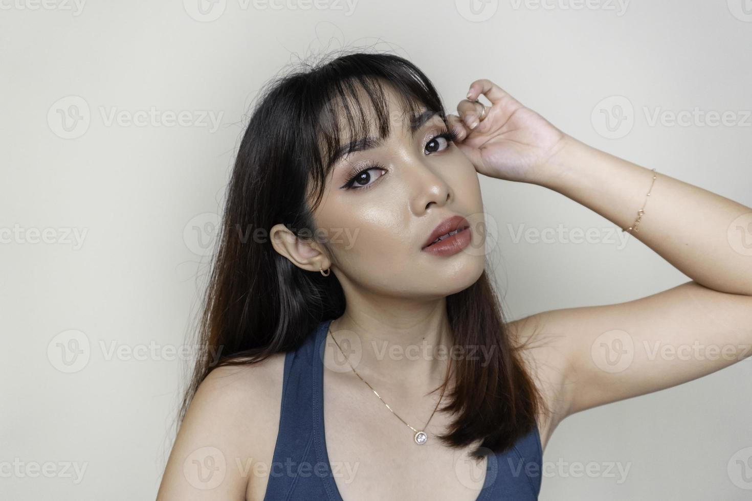 um rosto alegre de beleza da jovem modelo asiática vestindo top verde-azulado. maquiagem skincare beleza tratamento facial, spa, conceito de saúde feminina. foto