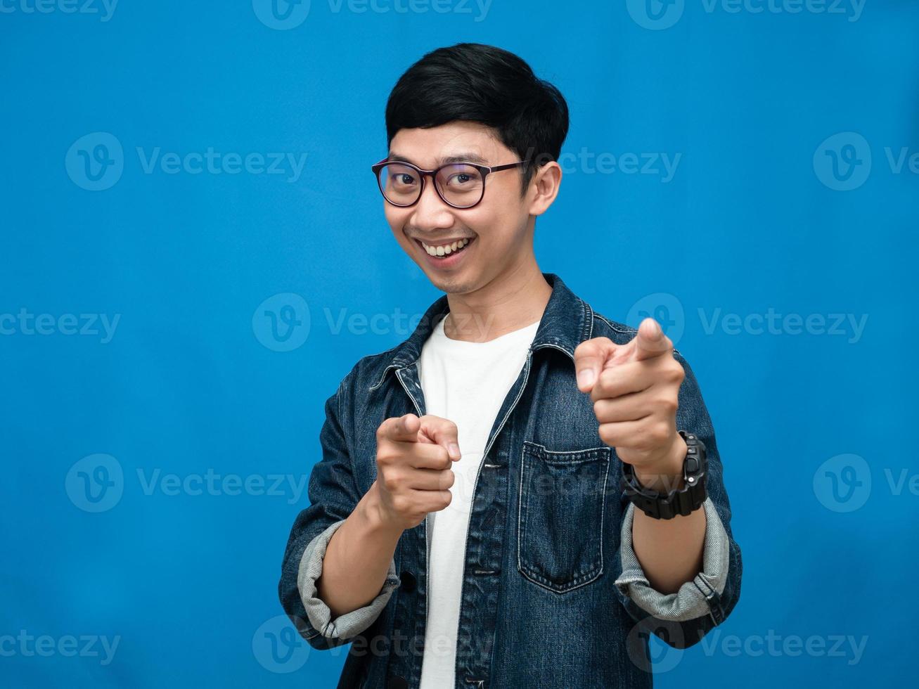 homem positivo gesto de camisa jeans aponte o dedo para você fundo azul foto