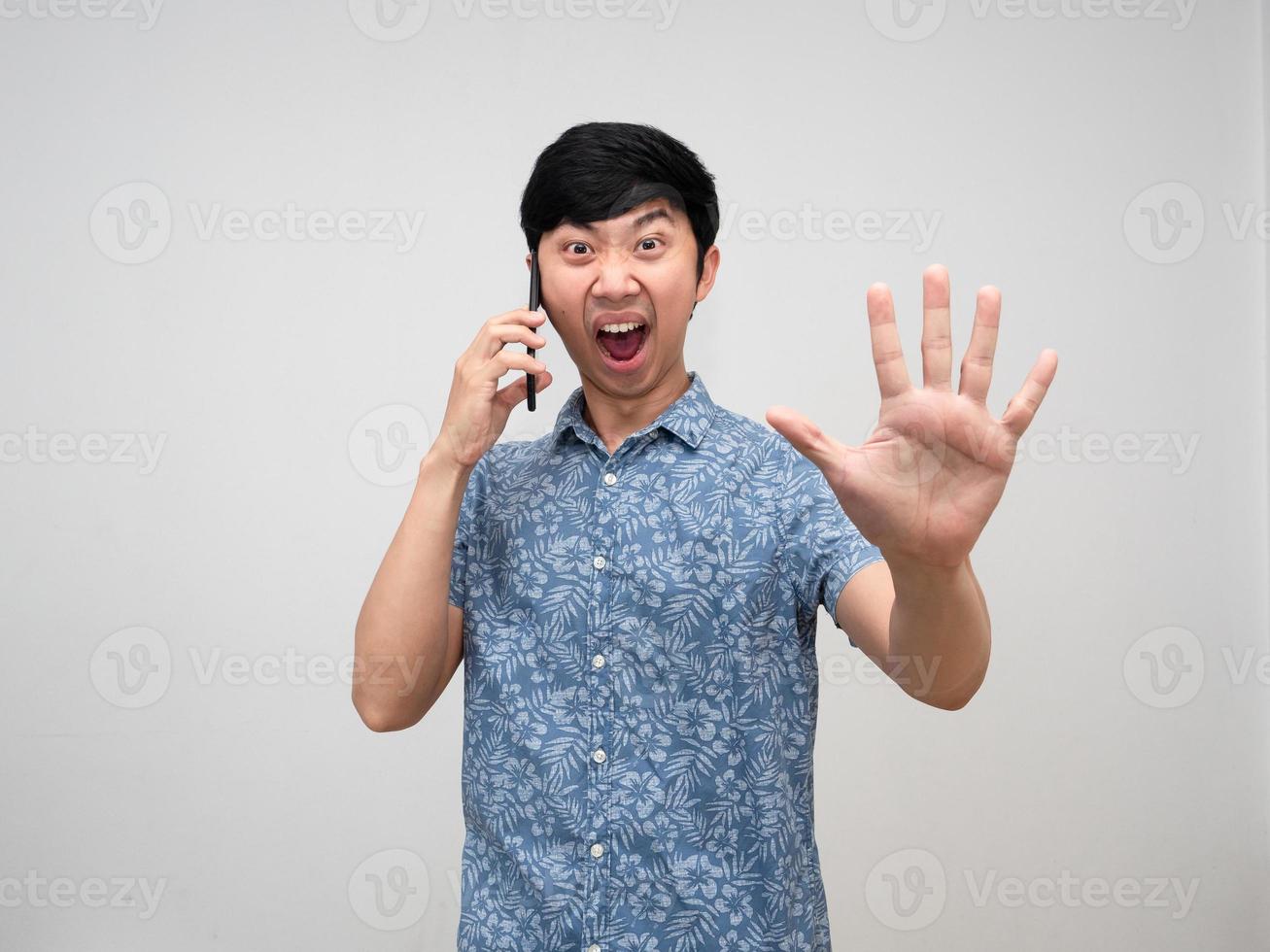 homem asiático camisa azul falando com celular sente raiva mostra parada de mão isolada foto