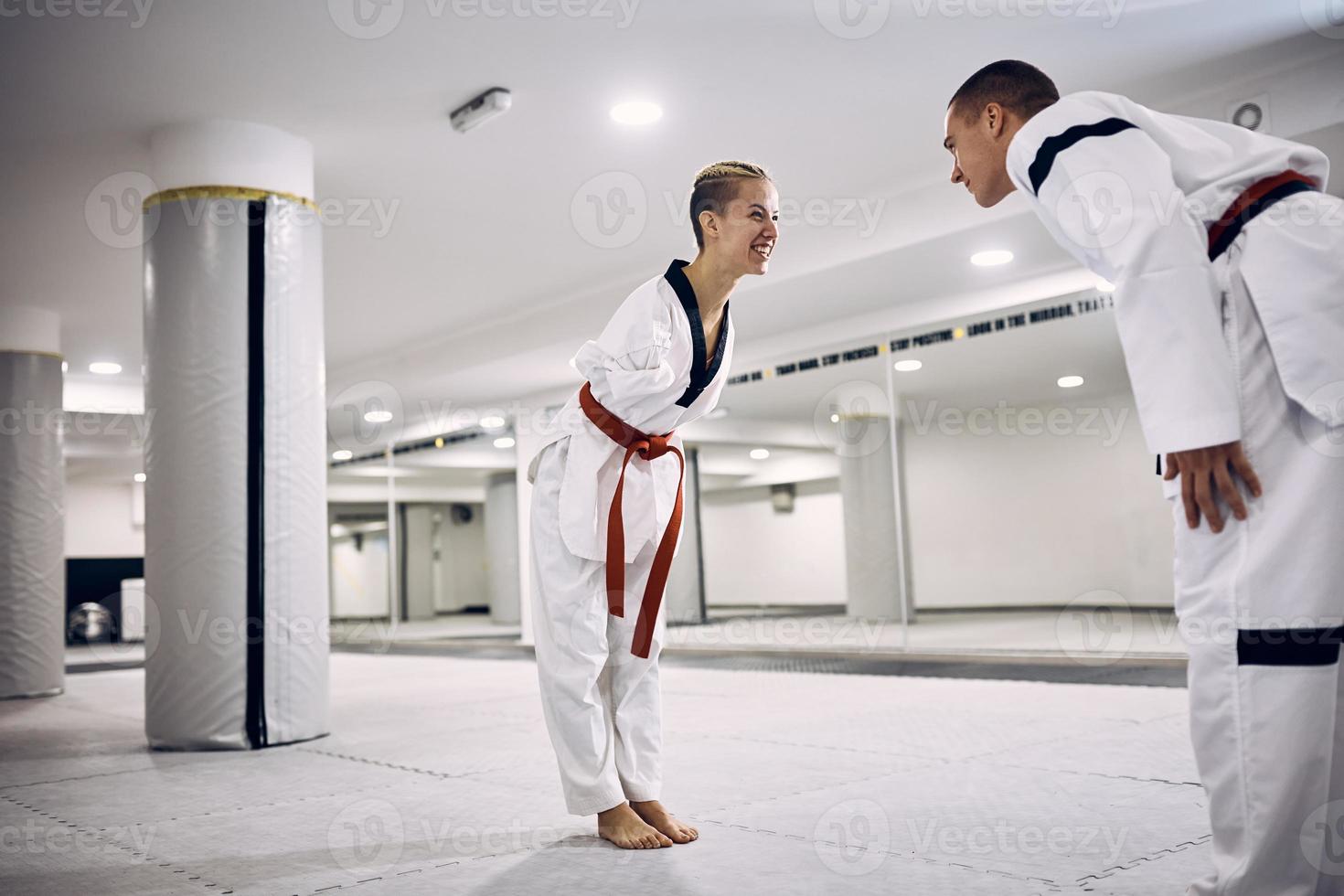 feliz lutadora de taekwondo com deficiência e seu parceiro poupador cumprimentam após o combate. foto