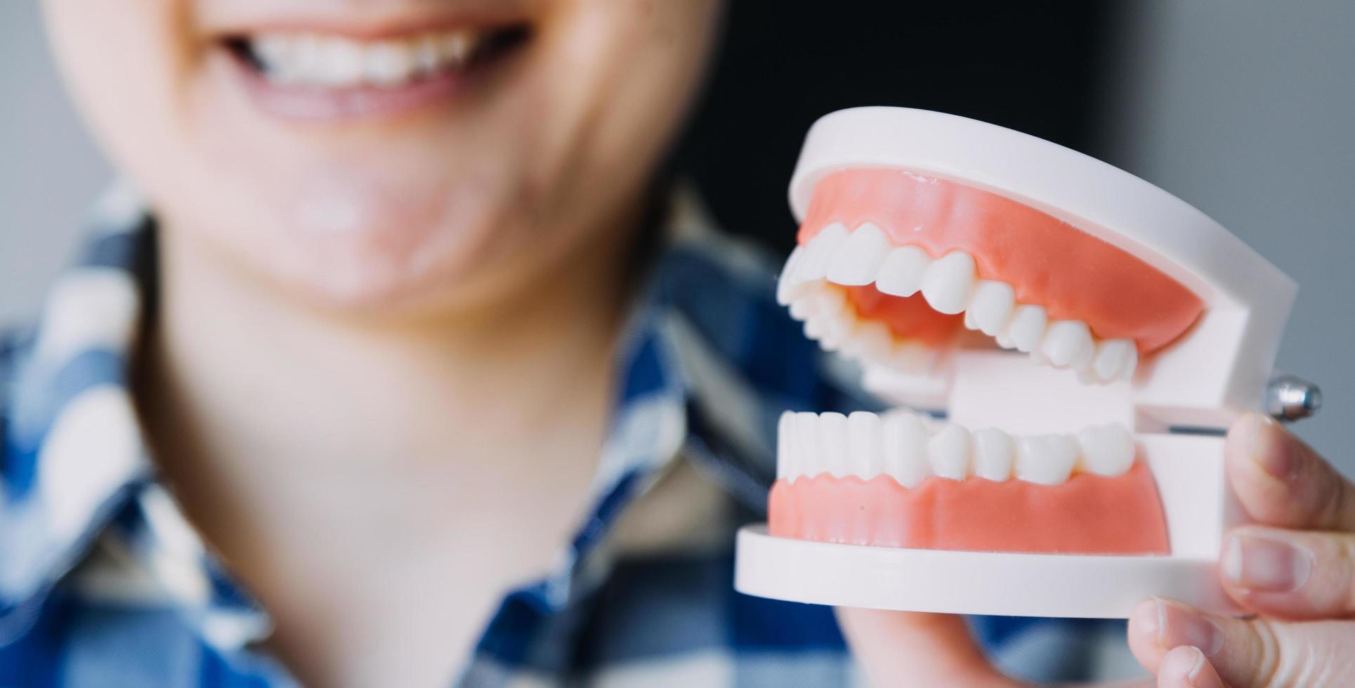 conceito de estomatologia, retrato parcial de menina com fortes dentes brancos, olhando para a câmera e sorrindo, dedos perto do rosto. closeup de jovem no dentista, estúdio, dentro de casa foto