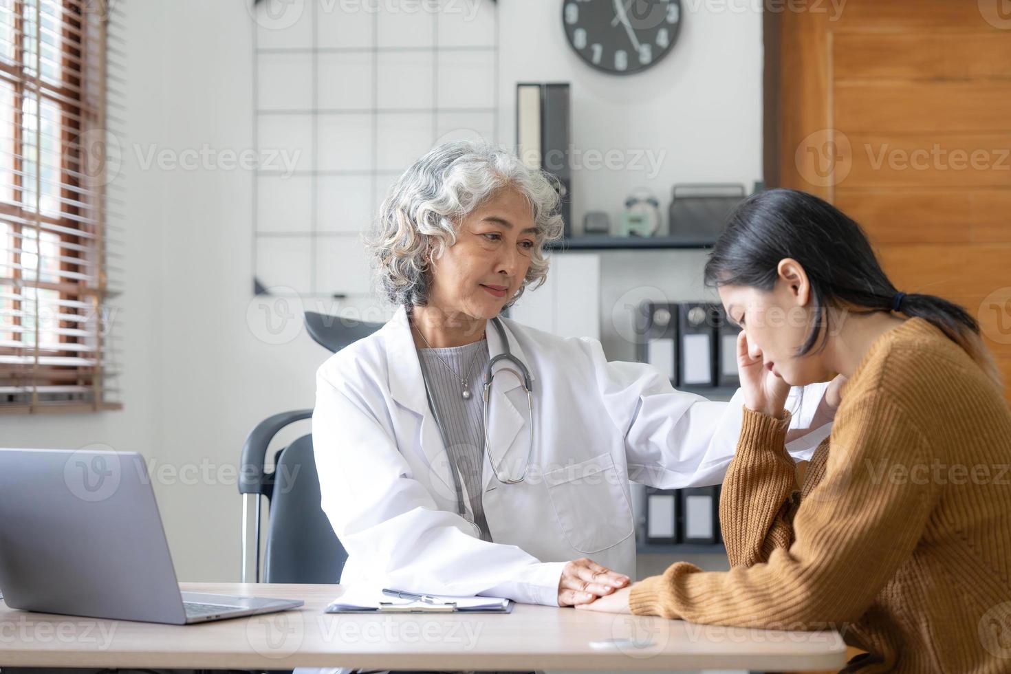 médico sênior auxiliando uma mulher em seu escritório. o paciente está chorando e se sentindo desesperado foto