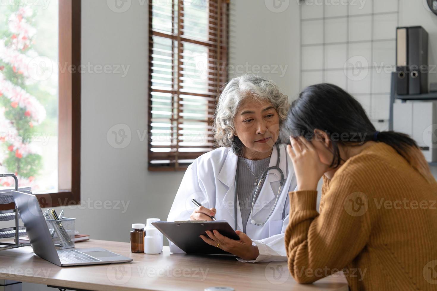 médico sênior auxiliando uma mulher em seu escritório. o paciente está chorando e se sentindo desesperado foto