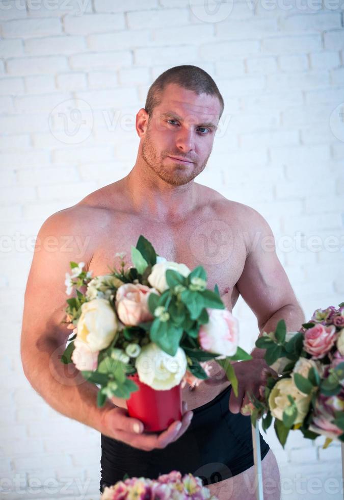 atleta masculino sexy com buquês de flores em fundo branco foto