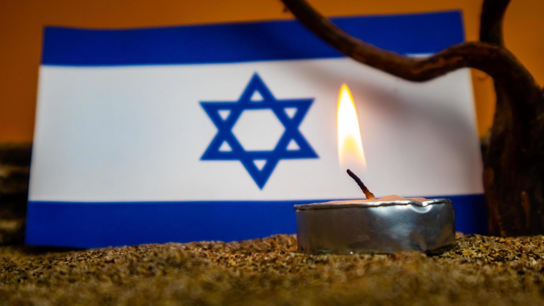 bandeira israelense e velas queimando na frente dela, dia da memória do holocausto foto