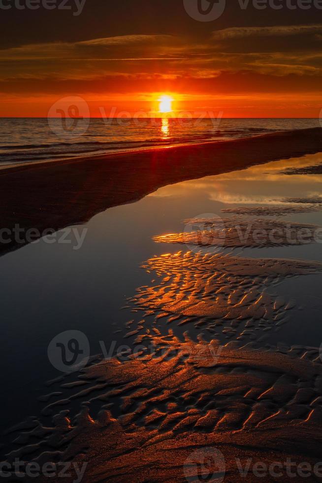 padrões na areia do mar ao pôr do sol foto