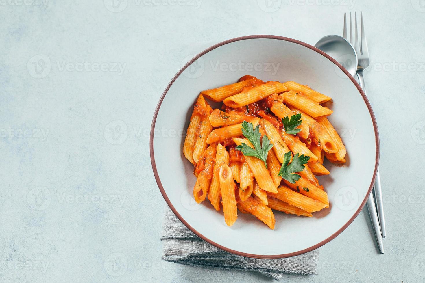 macarrão penne com sause de tomate em chapa branca na mesa de fundo de pedra. vista superior, copie o espaço foto