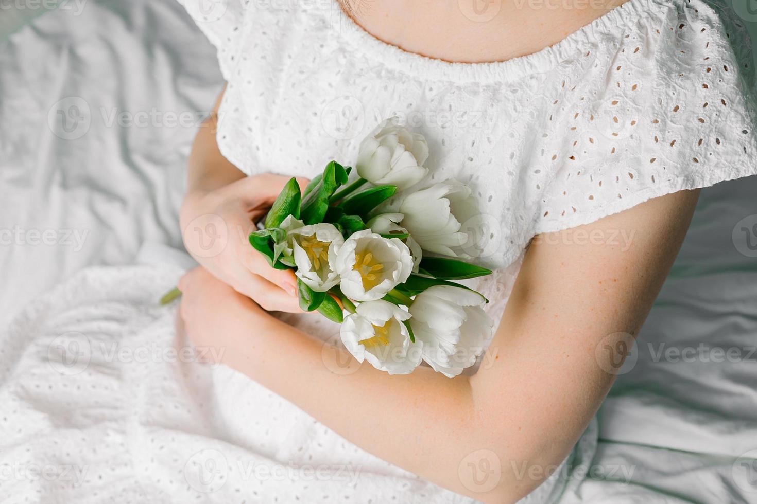 buquê de tulipas brancas nas mãos da mulher. conceito de dia internacional da mulher ou dia das mães. foto