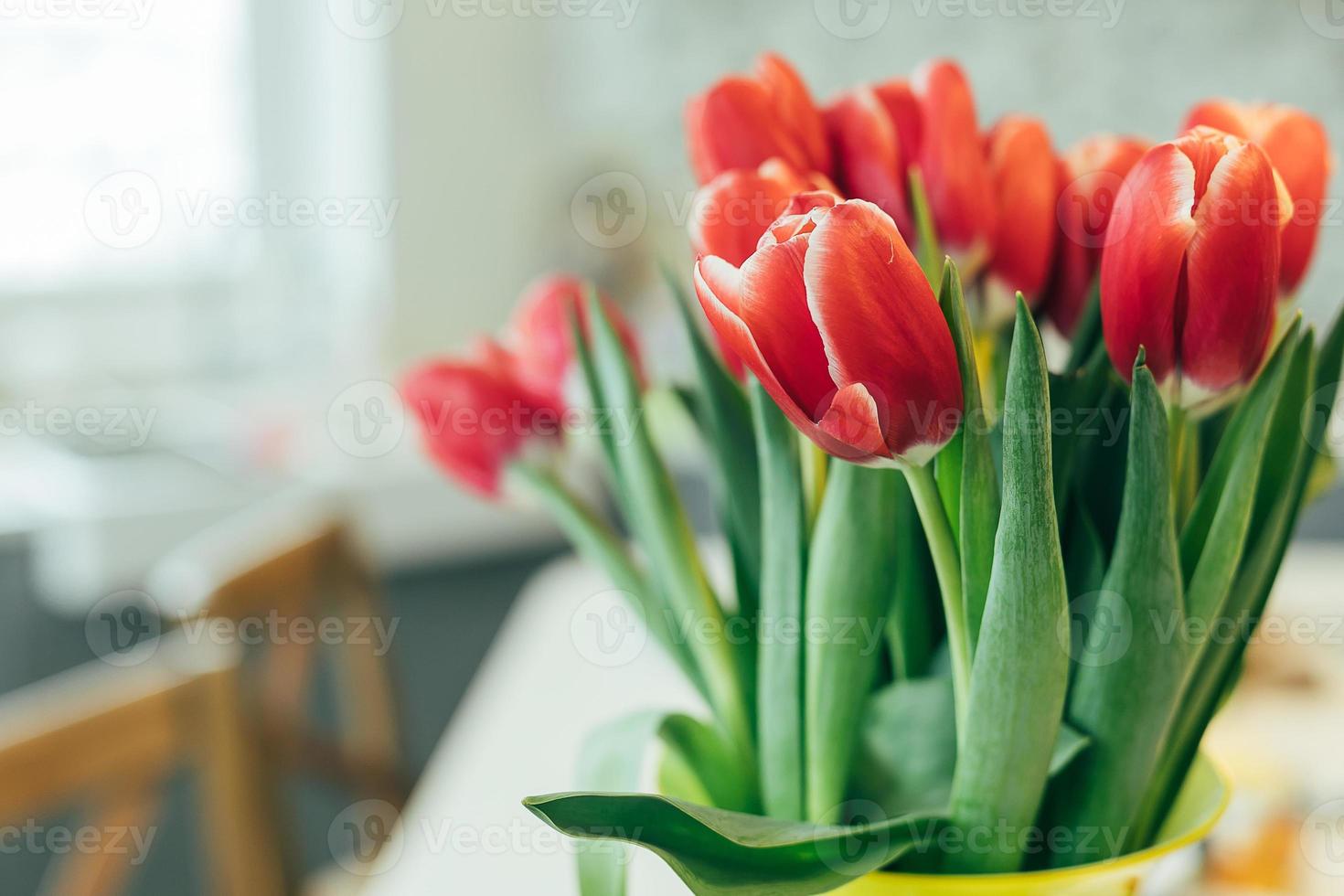 buquê fresco de tulipas vermelhas em um vaso na mesa da cozinha. estilo de vida, conceito de férias. copie o espaço. foto