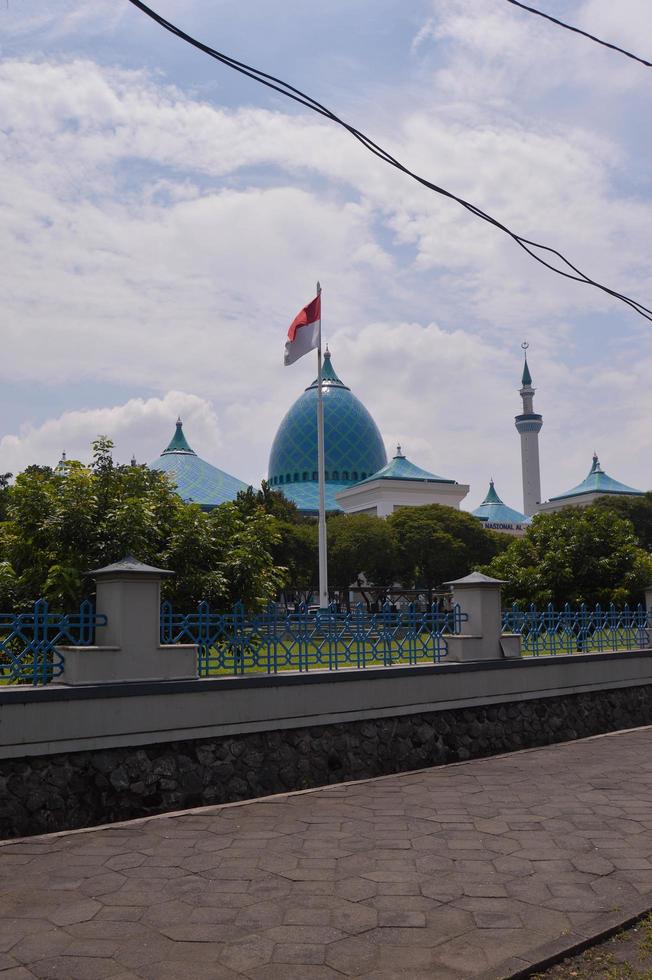 vista da grande mesquita com a cúpula e a bandeira indonésia na frente dela. foto