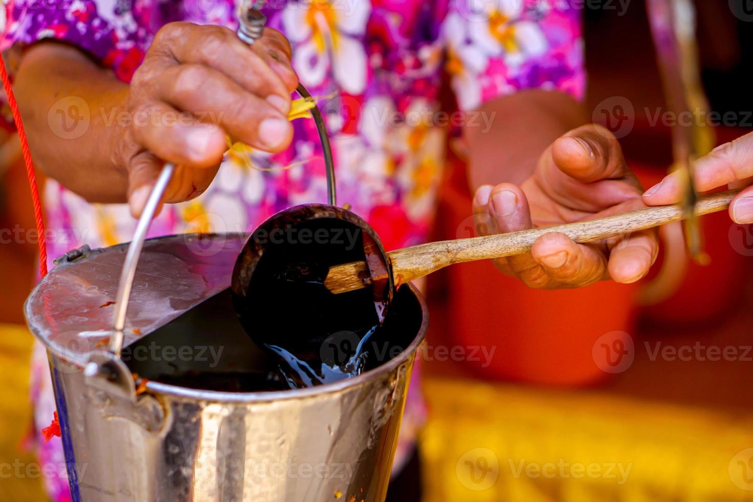 closeup mão de pessoas segurando casca de coco colher água do tanque para o banho das relíquias na tradição tailandesa lanna banho das relíquias. foto