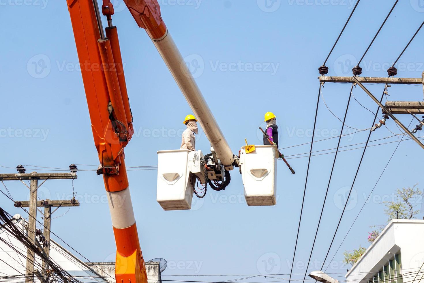 eletricistas trabalhando no teleférico para reparar a linha de energia sob o fundo do céu azul claro. foto