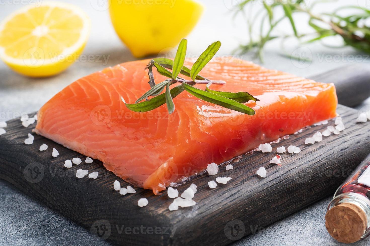 filé de salmão, peixe salgado vermelho em uma tábua de madeira. limão, especiarias de alecrim. foto