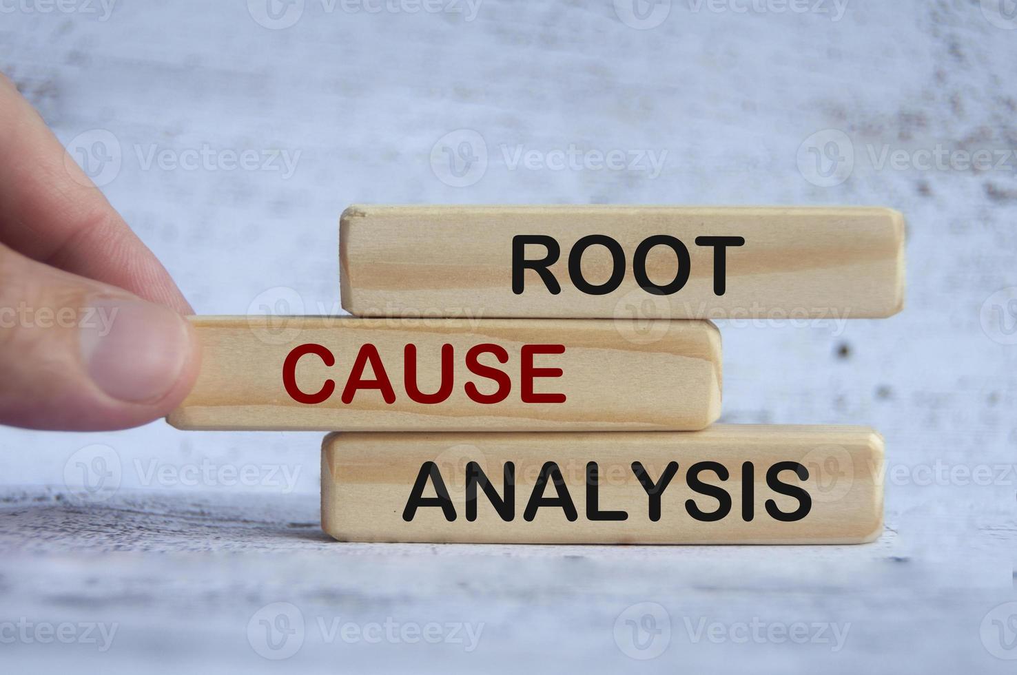 texto de análise de causa raiz em blocos de madeira com uma mão segurando um bloco de madeira. foto
