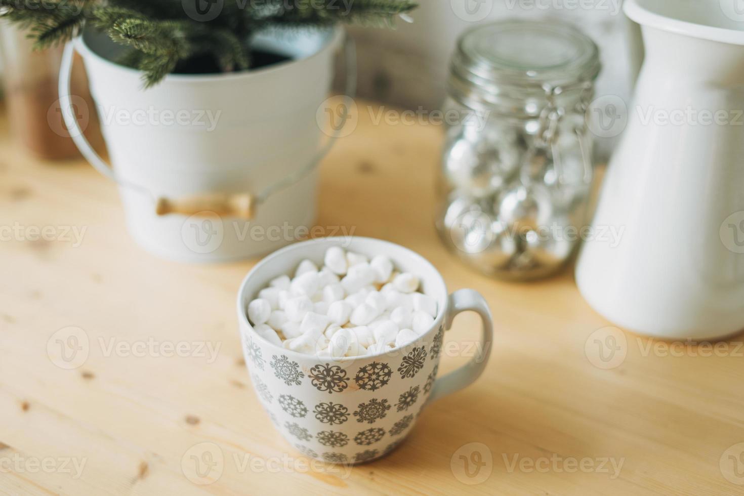 copo branco com cacau ou café com marshmallow na mesa da cozinha, clima natalino, casa aconchegante foto