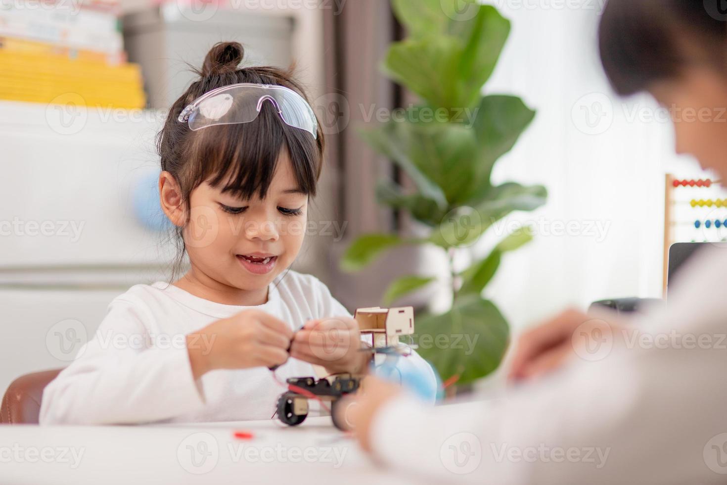 os alunos da ásia aprendem em casa na codificação de carros robóticos e cabos de placa eletrônica em haste, vapor, código de computador de tecnologia de ciência de engenharia matemática em robótica para o conceito de crianças. foto