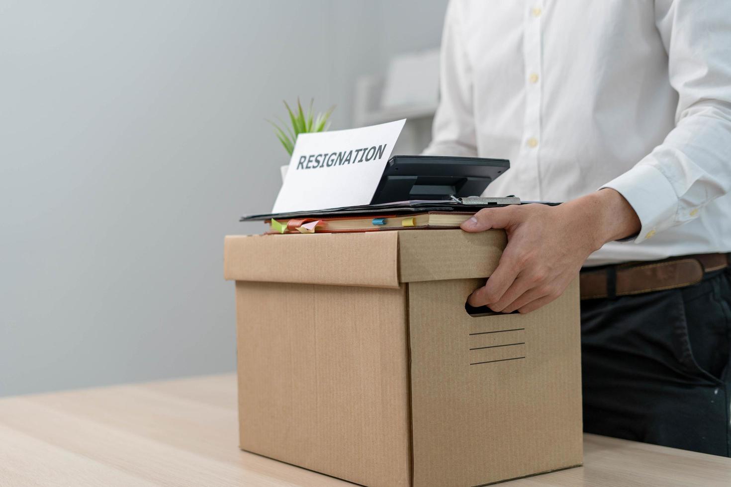 um empresário segura uma caixa para itens pessoais após enviar uma carta de demissão a um executivo ou chefe. incluir informações sobre demissão e vagas e mudanças de emprego. foto