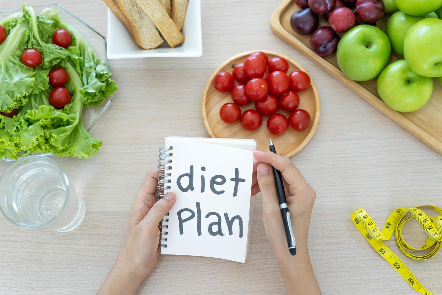 uma mesa de jantar com frutas, legumes e um plano de dieta. foto