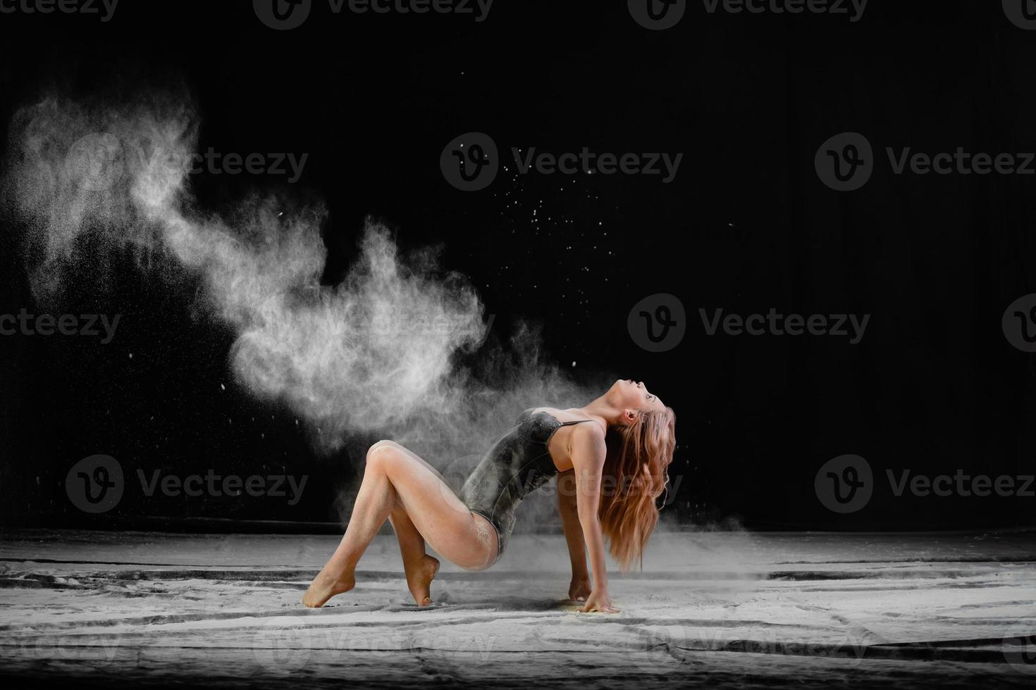 jovem mulher bonita com farinha espalhada no ar em um fundo preto foto