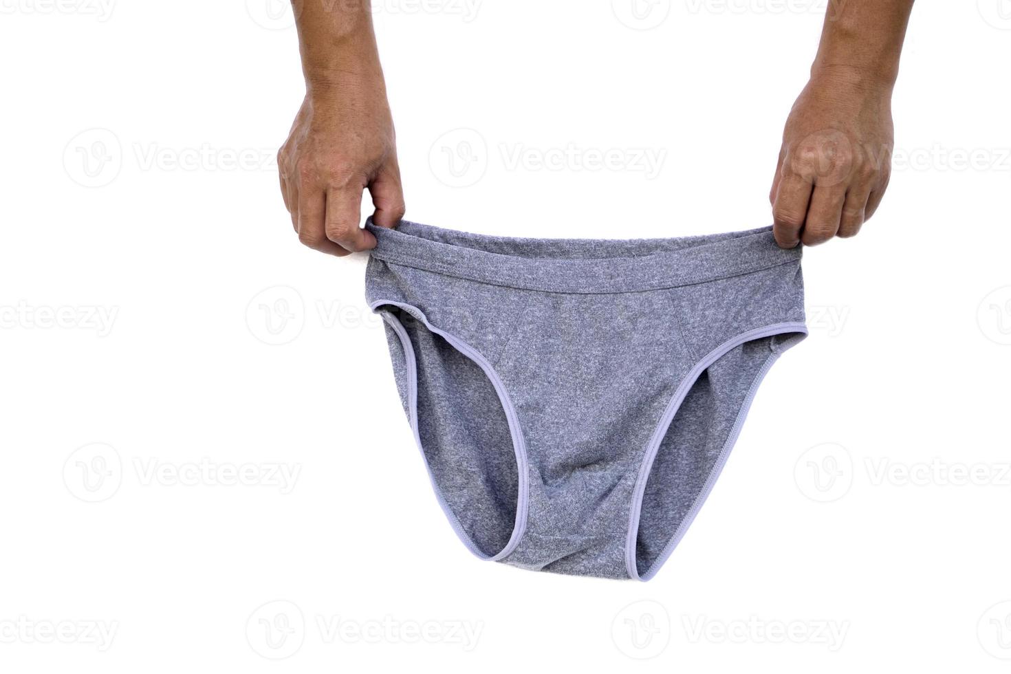 as mãos do homem seguram calças de cueca cinza para homens isolados no fundo branco. conceito, roupas e fantasias. moda masculina. vestindo todos os dias. foto