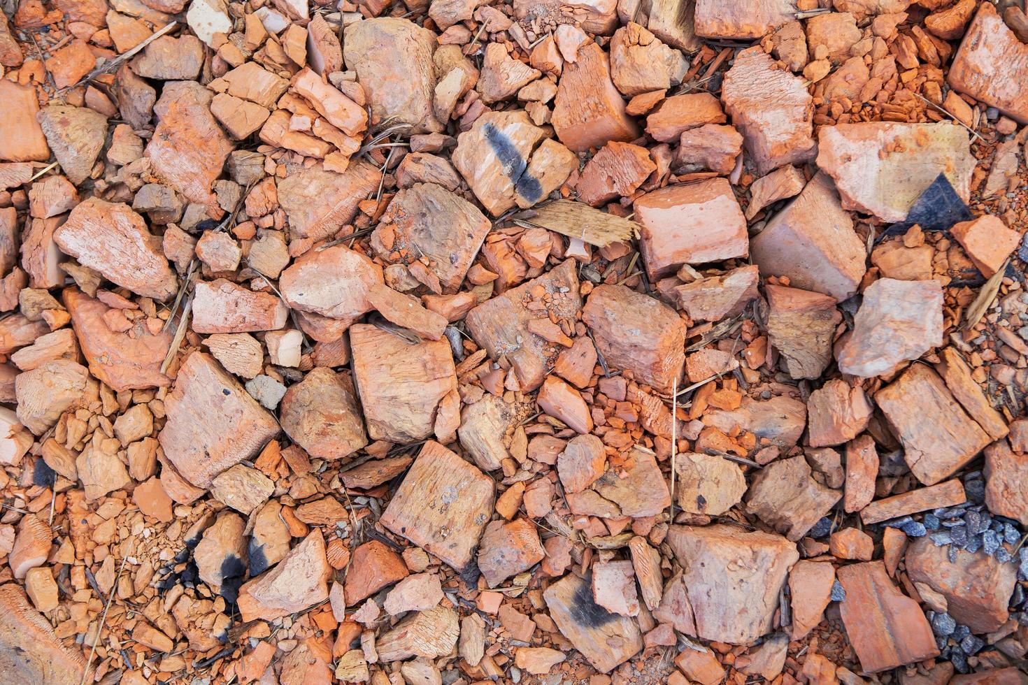 uma pilha de velhos tijolos de barro vermelho quebrados após a demolição de um edifício antigo encontra-se no chão em um canteiro de obras. foto