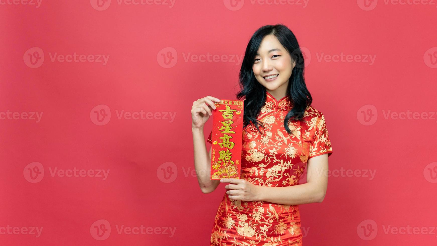 senhora com traje cheongsam vermelho ou qipao segurando cartão de fortuna de bênção isolado em fundo vermelho. texto chinês significa muita sorte grande lucro foto