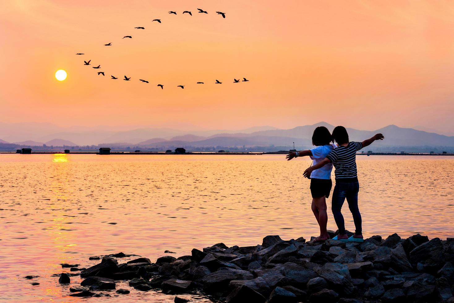 mãe e filha estavam felizes na água ao pôr do sol foto