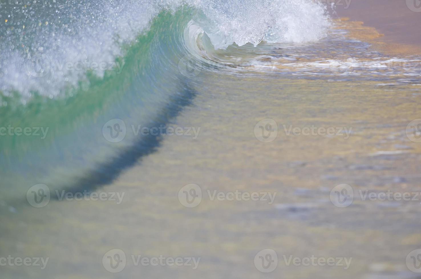 uma onda quebrando na costa de areia foto