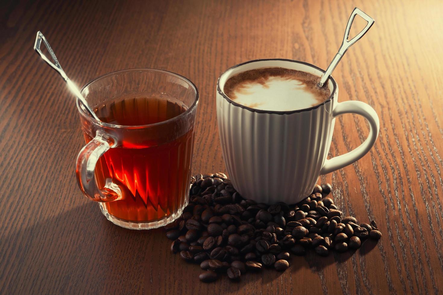 café quente com grãos de café e chá quente em fundo de madeira. foto