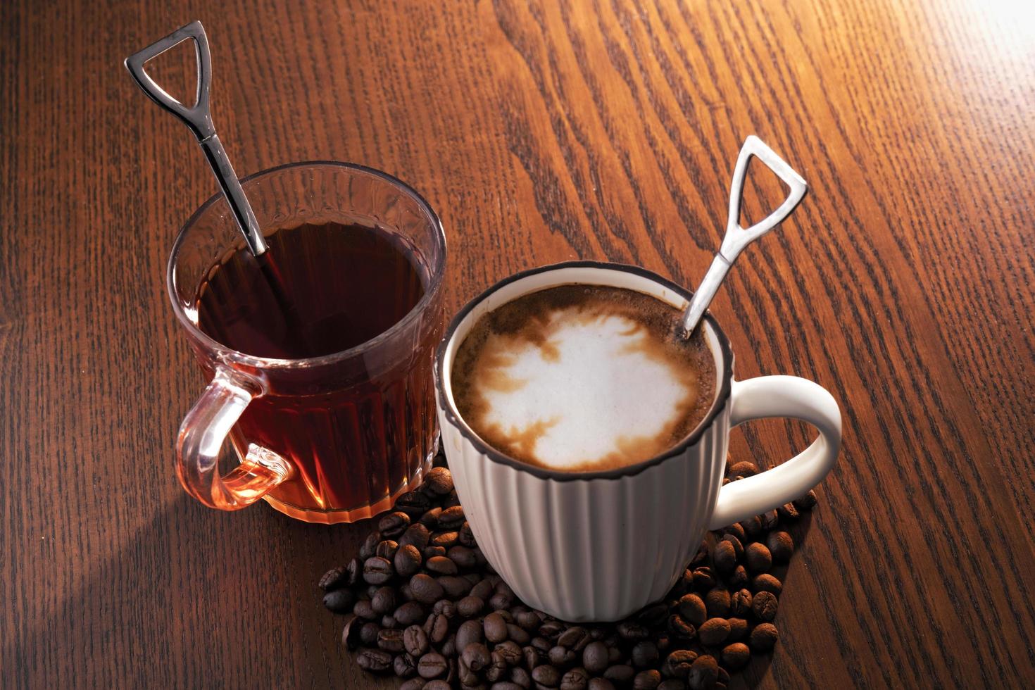 café quente com grãos de café e chá quente em fundo de madeira. foto