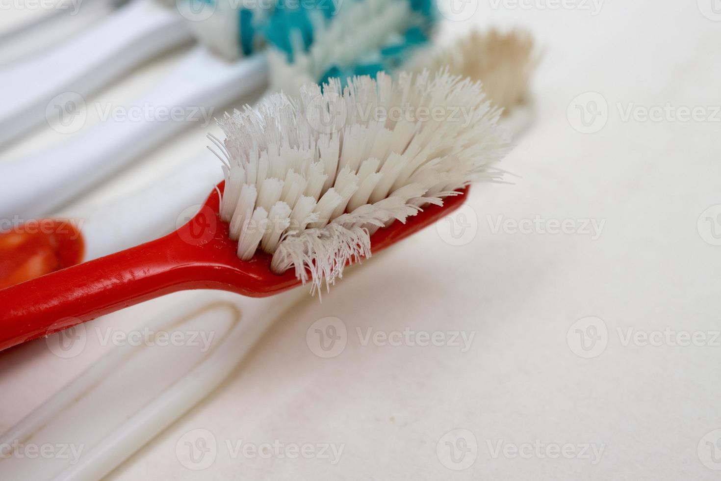 um monte de velhas escovas de dentes desgastadas com cerdas dobradas em um fundo branco foto