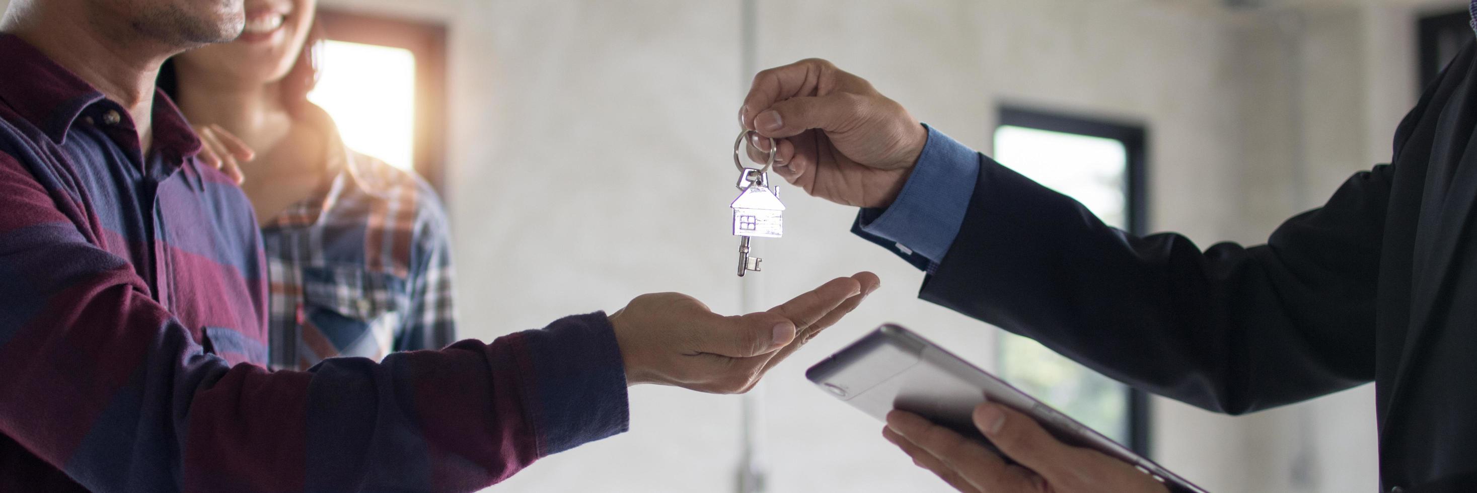 agente bancário dá a chave do apartamento ou residente ao jovem casal após uma discussão bem-sucedida e contrato finalizado, conceito imobiliário foto