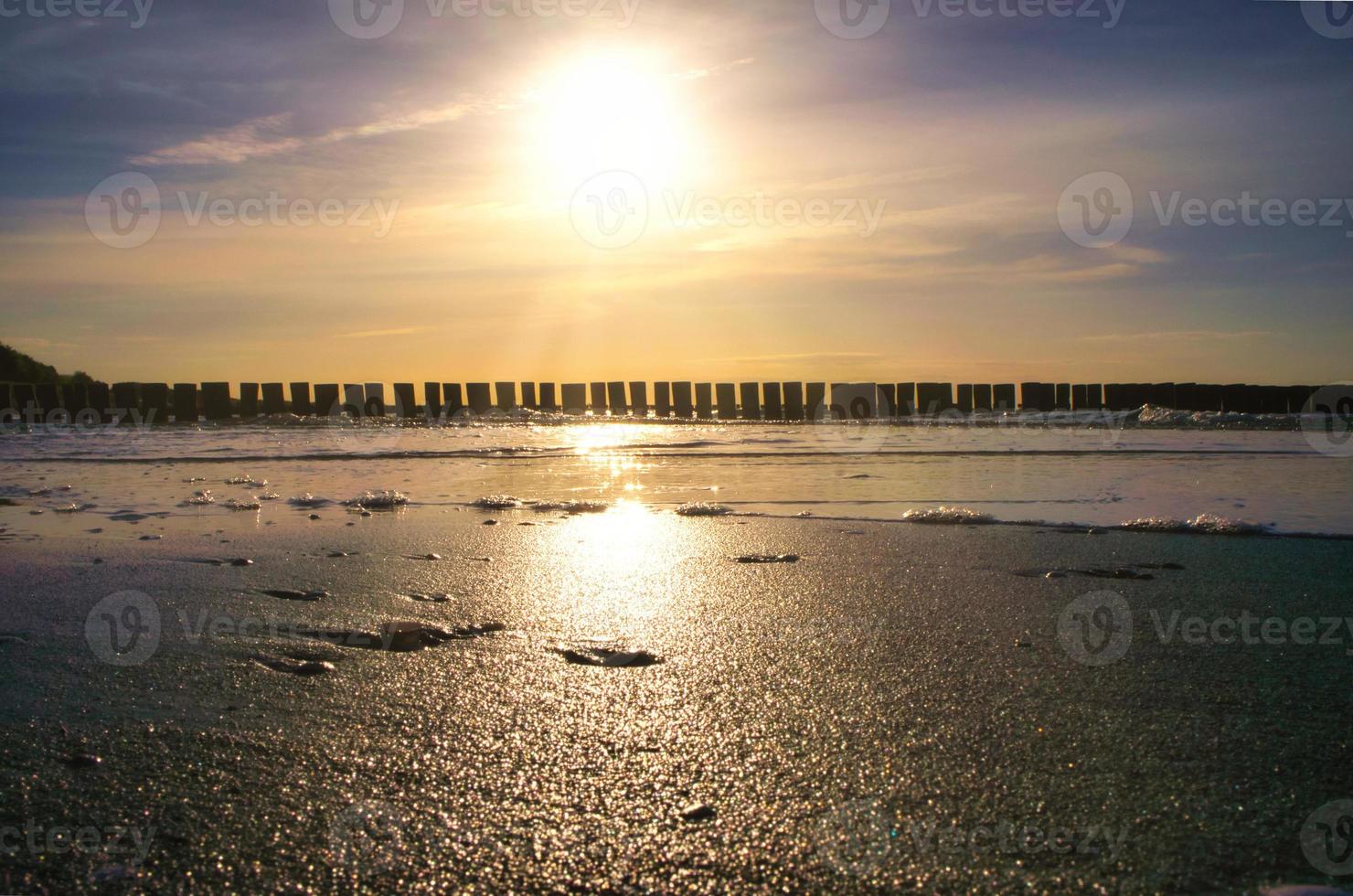 espigões projetam-se para o mar ao pôr do sol. o sol brilha no mar báltico. panorama foto