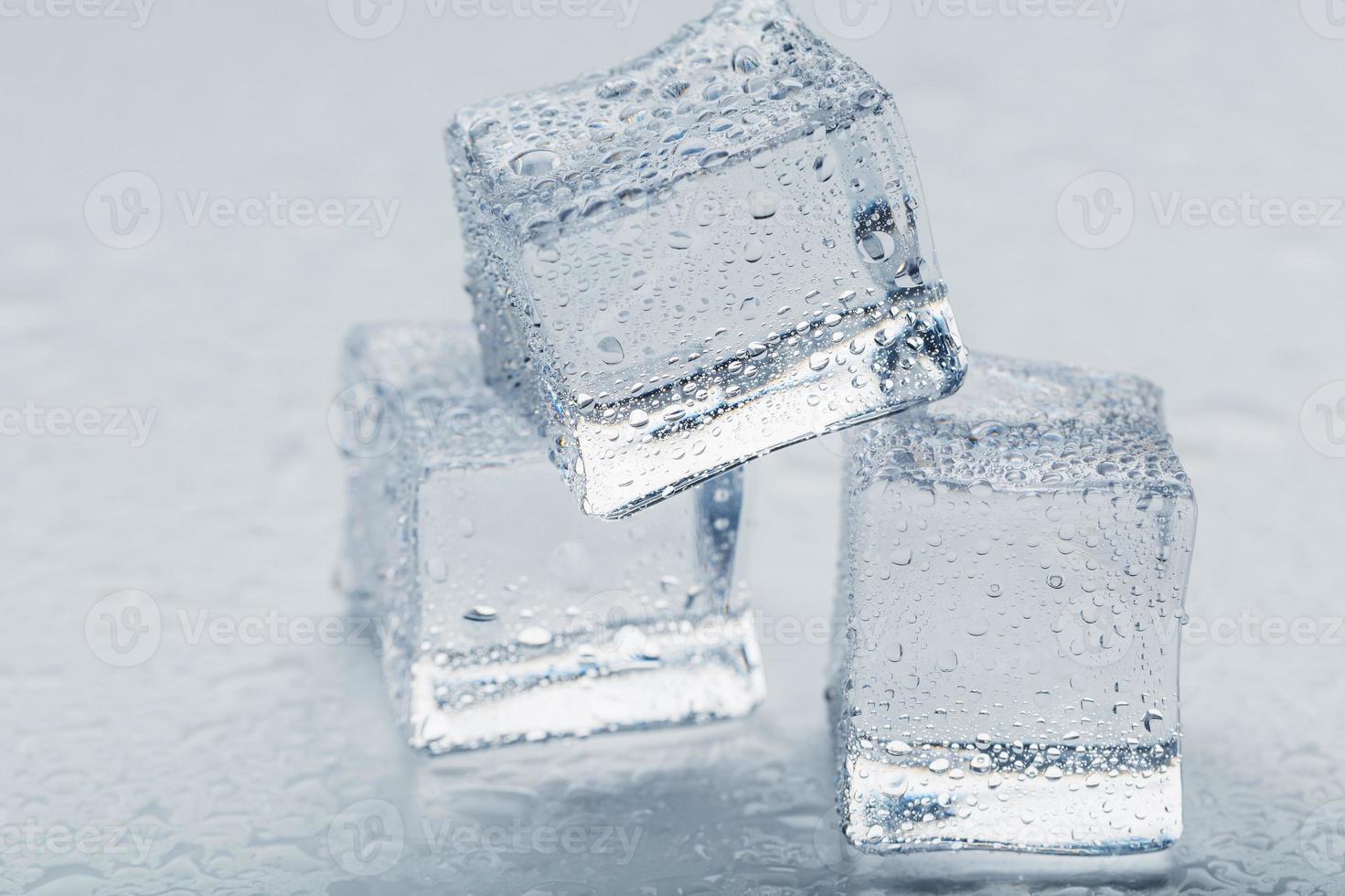 cubos de gelo na forma de uma pirâmide com água cai de perto - em macro sobre um fundo branco. foto