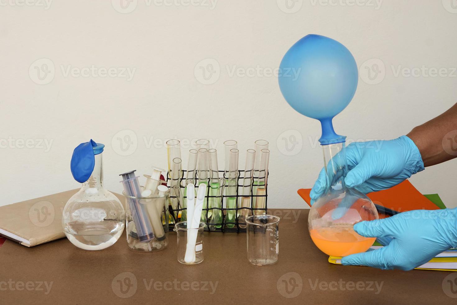 aluno faz experimento científico, aula de laboratório, garrafas transparentes com balões inflados em cima da garrafa. o experimento sobre a reação do ar ou gás usando substâncias químicas. assunto de ciência da educação foto