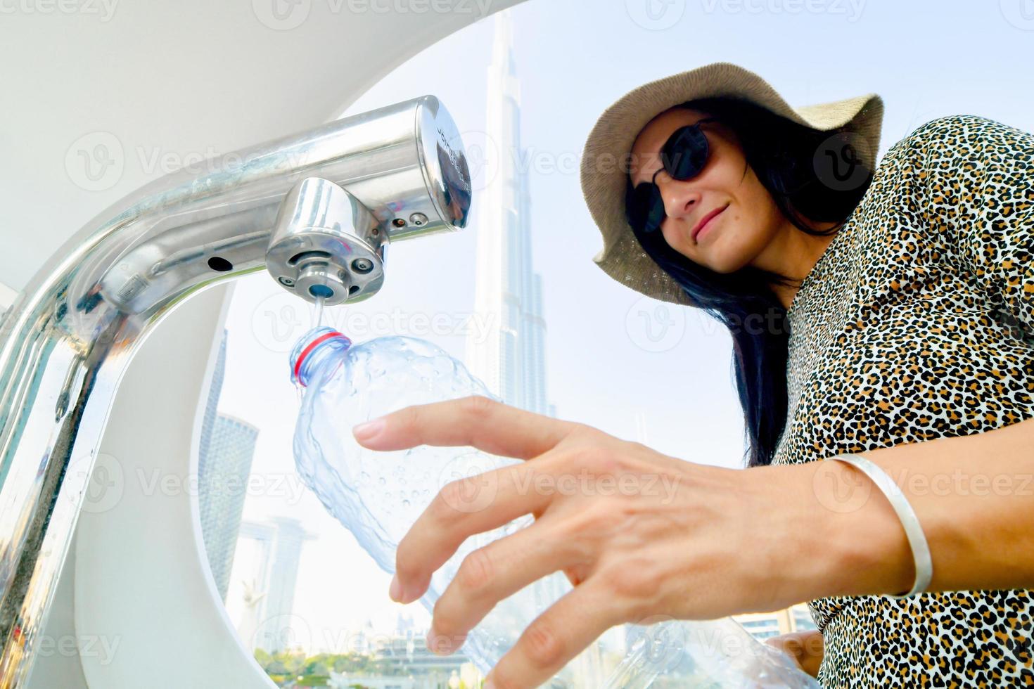 dubai, emirados árabes unidos, 2022 - mulher turista usa máquinas de recarga de água em locais públicos para turistas. salve a terra, economize água e reduza o conceito de plástico foto