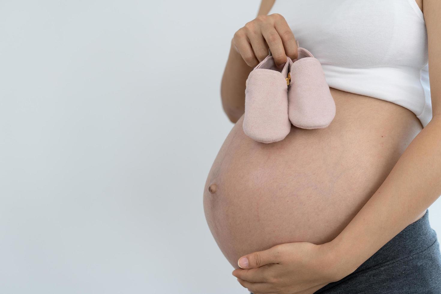 as mulheres grávidas gostam de sapatos de bebê. novas mães preparam roupas para o próximo bebê. gravidez com 30 semanas. foto