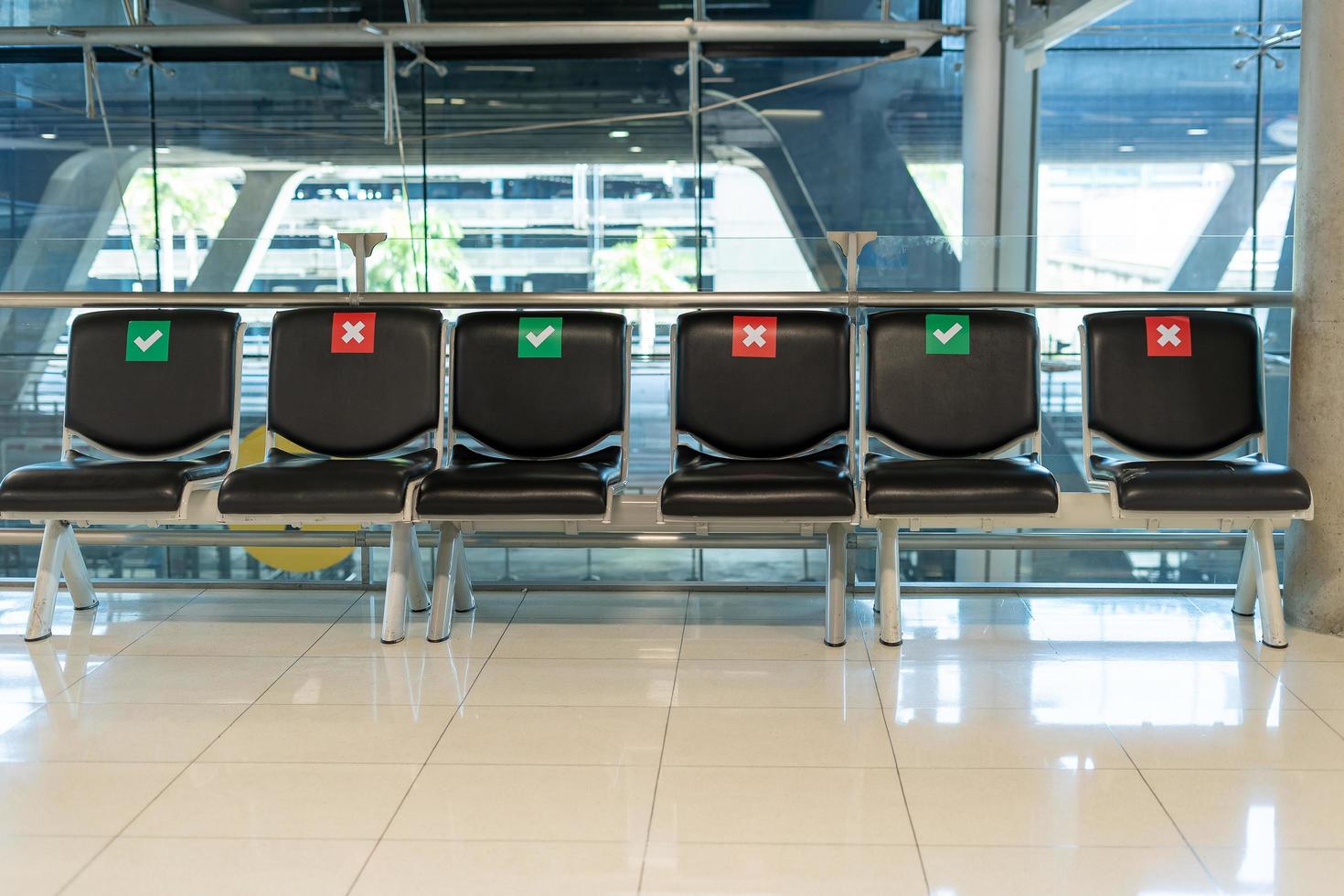 layouts de cadeiras públicas espaçadas socialmente durante a situação covid-19 no terminal do aeroporto. conceito de distância social. foto