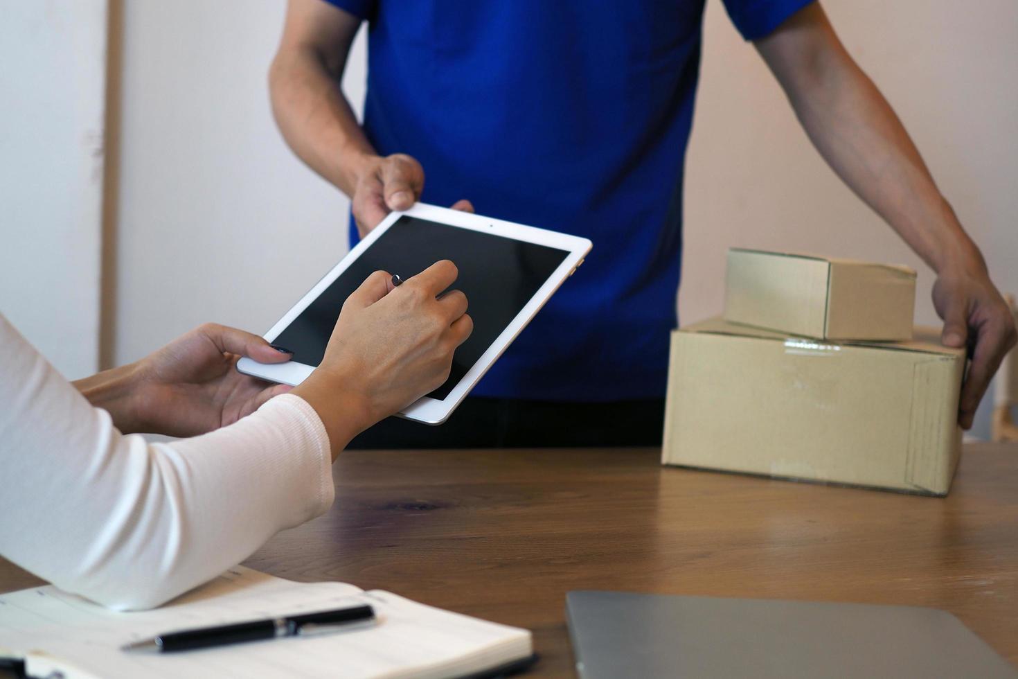 a garota compradora assina no tablet para receber a caixa do pacote do entregador. serviço de entrega rápida foto