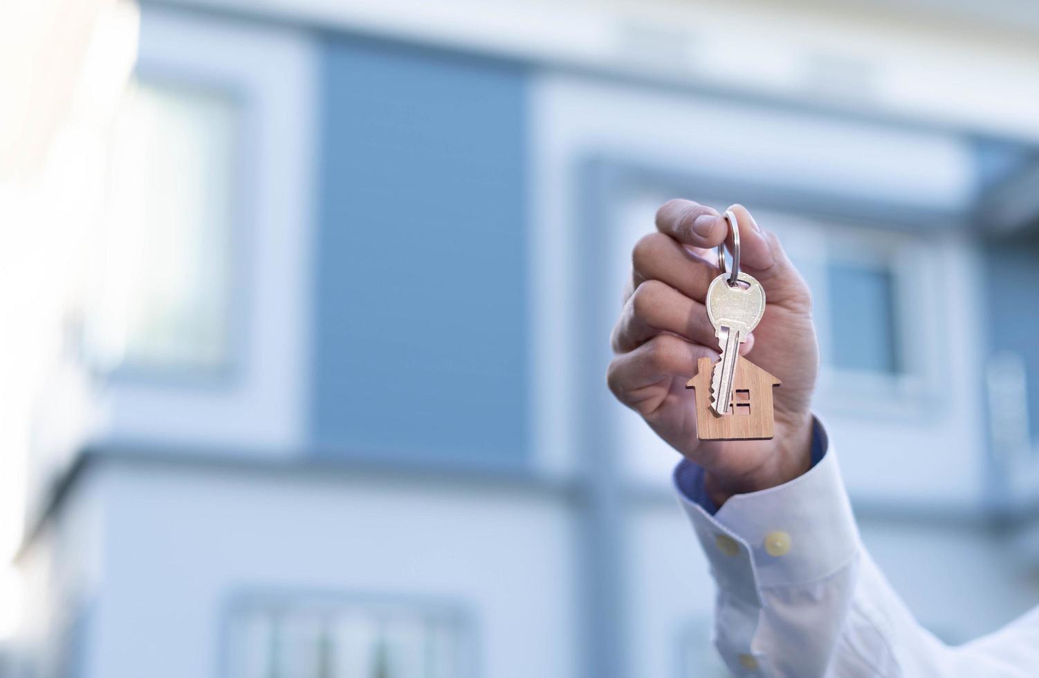 proprietário segurando uma nova chave de casa de um corretor depois de concordar em comprar um investimento em casa hipotecária. conceito de comprar uma casa, um novo lar. foto