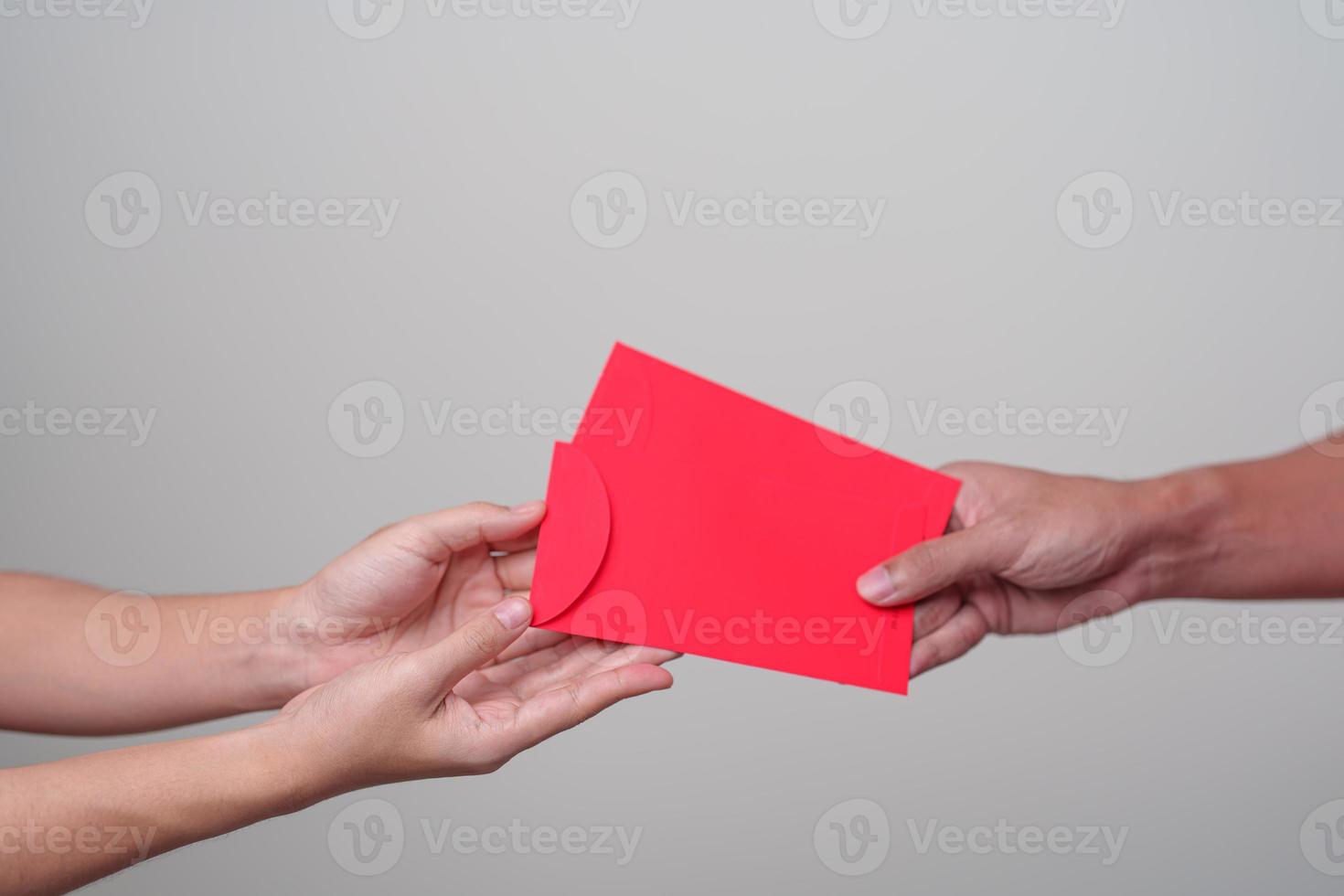 mão de pessoas dando envelope vermelho chinês, presente de dinheiro para feliz feriado do ano novo lunar foto