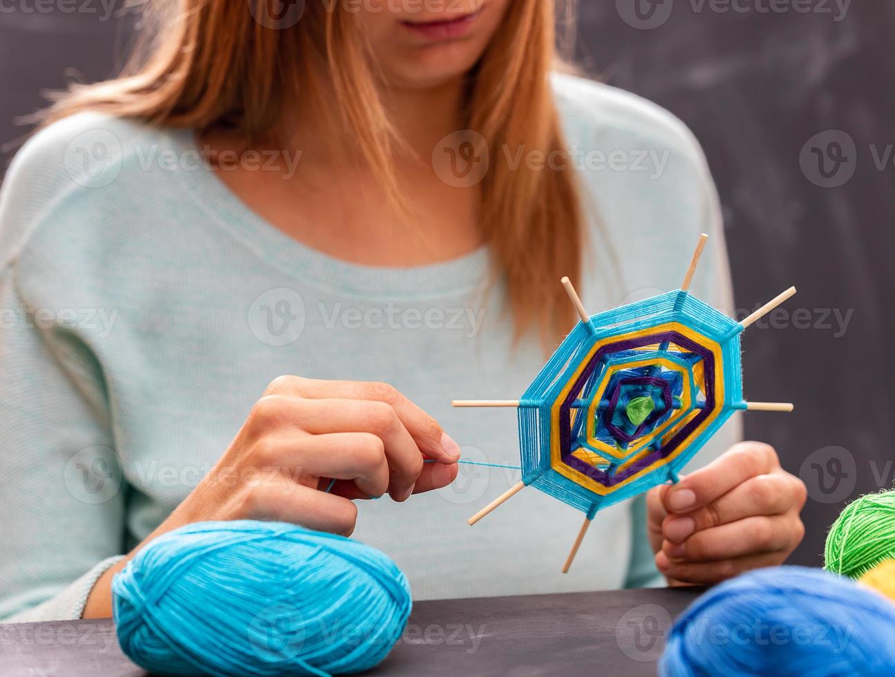 jovem está fazendo mandala artesanal de fios coloridos. foto